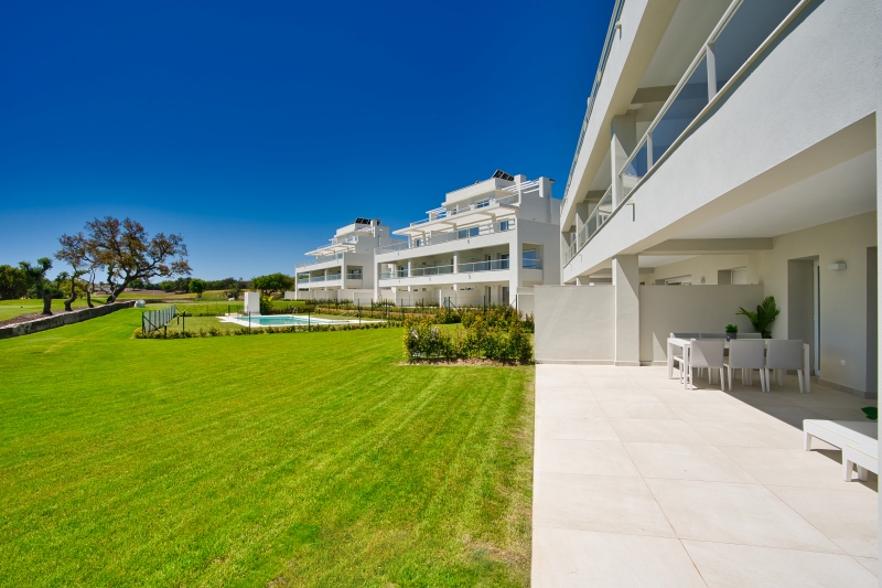 A new build apartment complex featuring a grassy lawn and swimming pool in San Roque, Cadiz.
