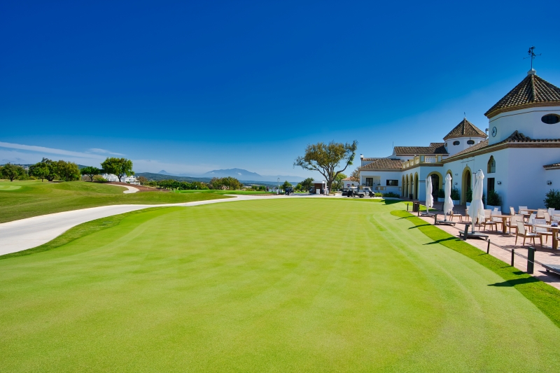 A golf course with a large house in the background located in San Roque.