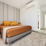 A newly constructed bedroom with a bed and vibrant orange accents.
