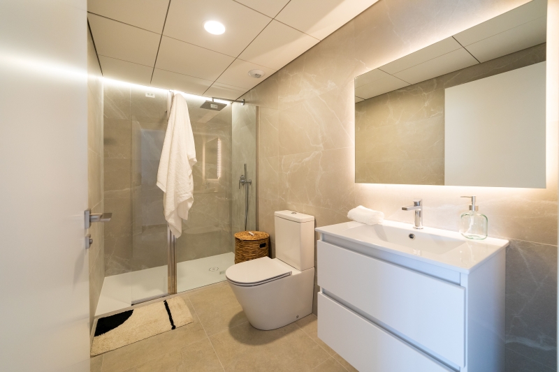 A white bathroom with a toilet and shower in an Alicante New Build Apartment.