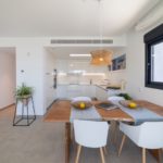 A modern apartment with a dining table and chairs in Alicante for sale.