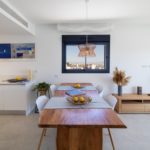 A white kitchen with a wooden table and chairs in a Gran Alicante new build apartment.