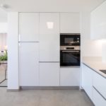 A modern kitchen with white cabinets and a microwave in an Alicante property for sale.