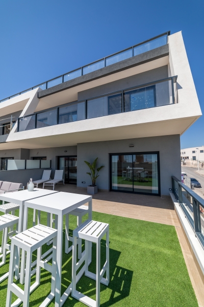 A modern Alicante apartment with white furniture and a green lawn.