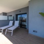 Alicante New Build Apartment with a balcony adorned with lounge chairs and a plant.