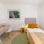 A small bedroom with a bed and a desk located in a Gran Alicante New Build Apartment.