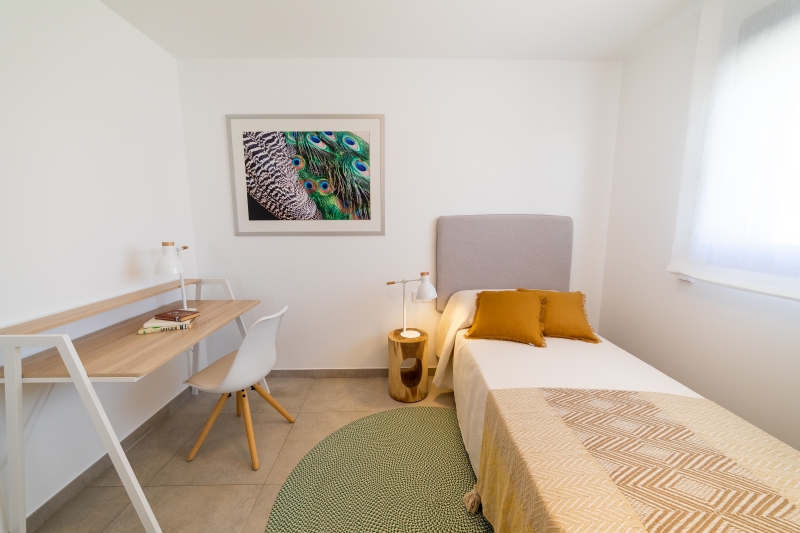 A small bedroom with a bed and a desk located in a Gran Alicante New Build Apartment.