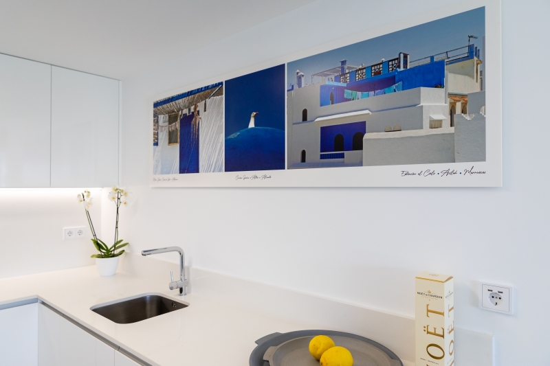 A white kitchen with a picture on the wall in an Alicante New Build Apartment.