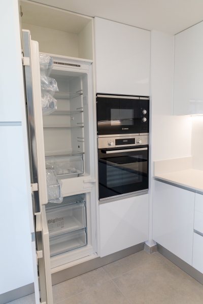 A white kitchen with a refrigerator and a microwave in a cheap Alicante property for sale.