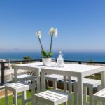 A white table and chairs on a deck overlooking the ocean in Alicante, alicante property for sale.
