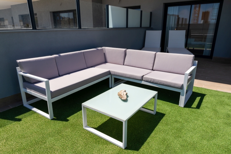 A white sectional sofa set on a grassy patio in Alicante.