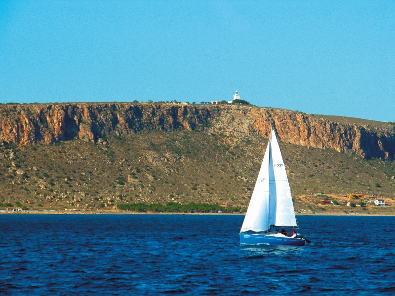 A sailboat is sailing in the water near a hill in Alicante.
