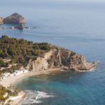 A stunning aerial view of a beach and cliffs in Alicante, with properties for sale.