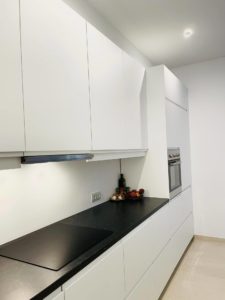 A white kitchen with a black countertop, recently renovated in Sitges.