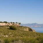 A view of a hillside with Alicante new build apartments and mountains in the background.