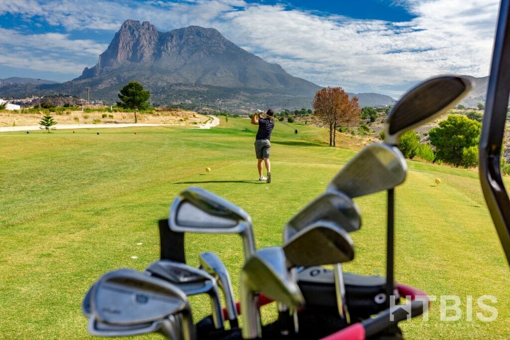 Golf clubs in a bag with a mountain in the background, overlooking a cheap Alicante property for sale.