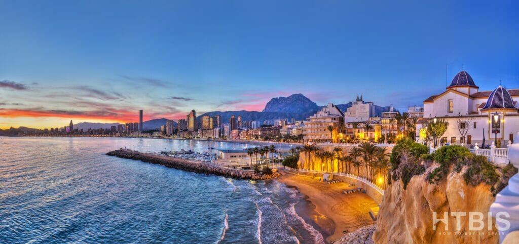 A city at dusk with mountains in the background and Benidorm property for sale.