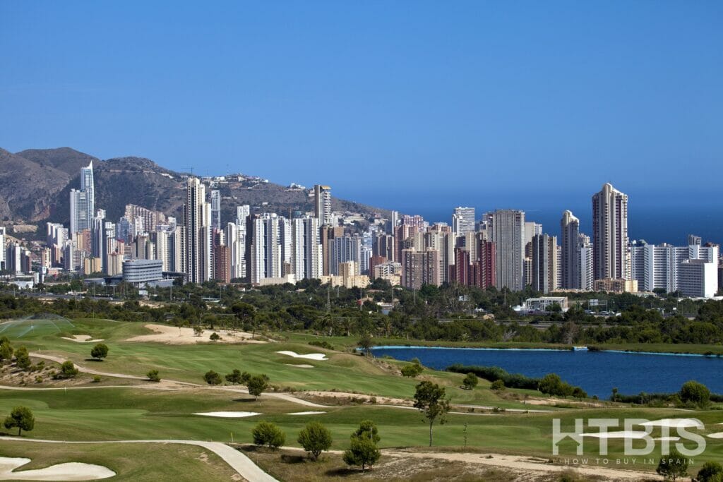 A golf course with a city skyline in the background and cheap Alicante property for sale.