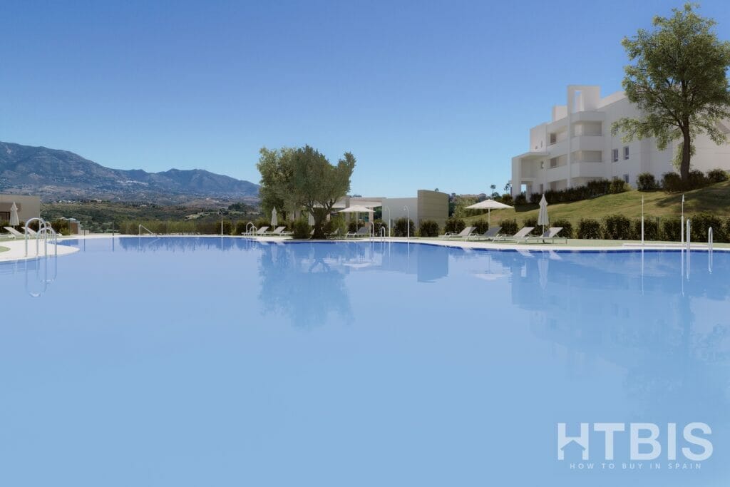 A swimming pool in front of a New Build Apartment in Mijas with mountains in the background.