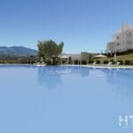 A swimming pool in front of a New Build Apartment in Mijas with mountains in the background.