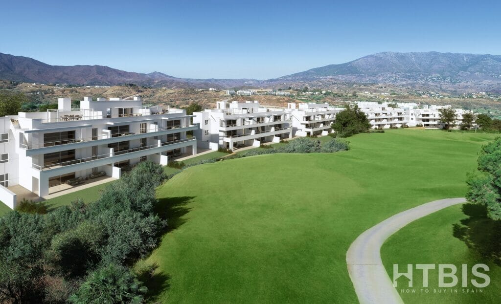 An aerial view of a Marbella New Build apartment complex with a golf course and mountains in the background.