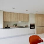 A kitchen with white cabinets and orange chairs in a Fuengirola New Build apartment.