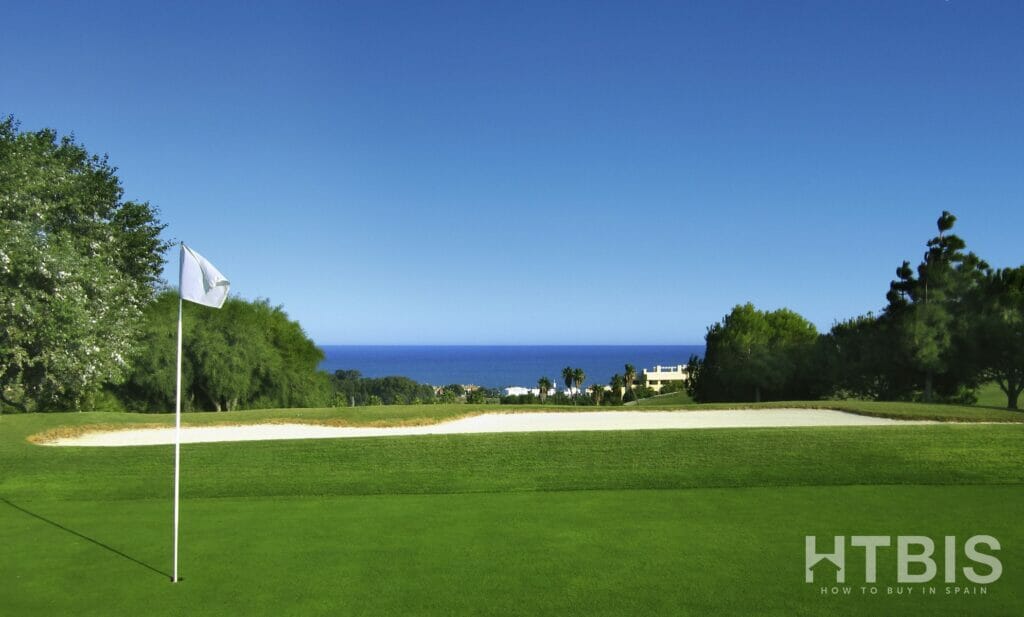 An Estepona golf course with a flag and ocean in the background.