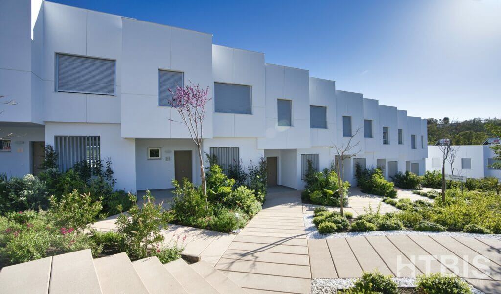 A white townhouse with a walkway and plants.