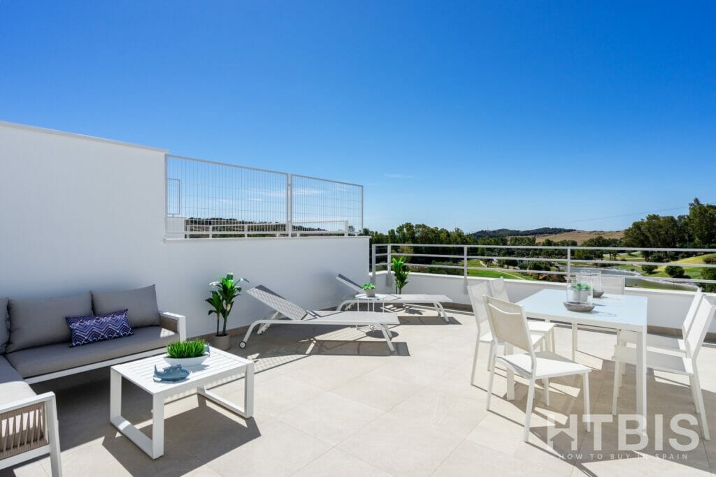 A balcony with white furniture and a view of the Estepona golf course.