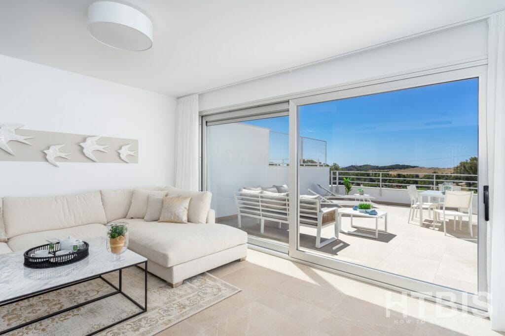 A white living room in a townhouse with a balcony overlooking the sea.