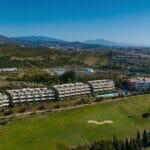 An aerial view of the Estepona apartment complex with a golf course and mountains.