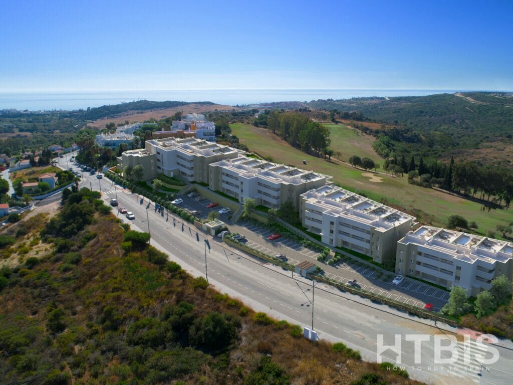 An aerial view of an apartment complex on a hillside overlooking the Estepona Golf Course.