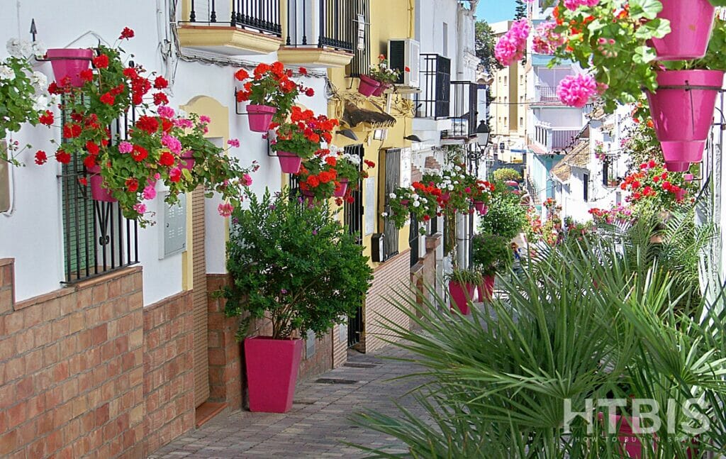 A narrow street lined with pink flower pots leads to an apartment near Estepona Golf Course.