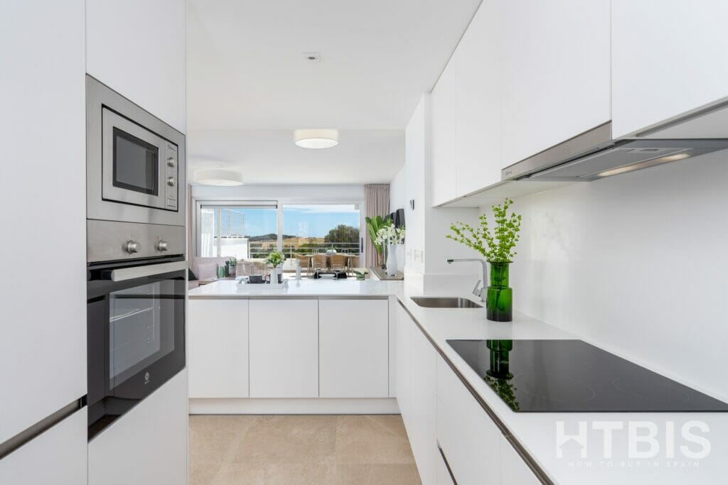 A white kitchen with stainless steel appliances in a townhouse overlooking the Estepona Golf Course.