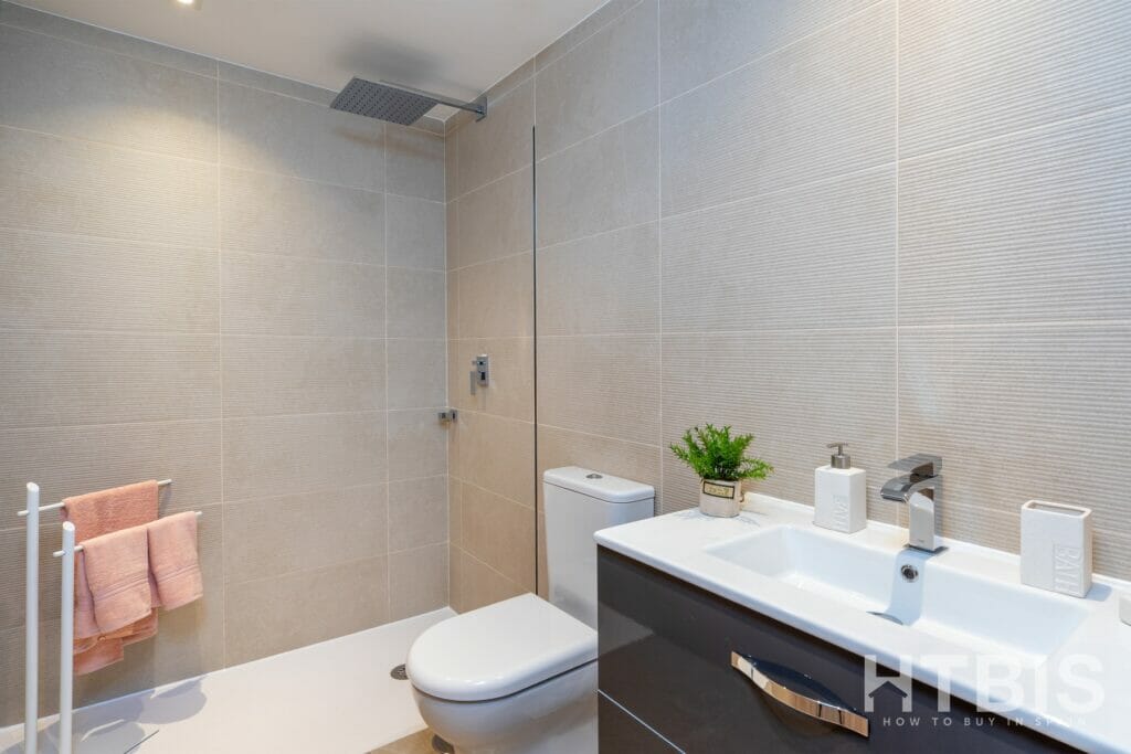 A bathroom in a townhouse with a toilet, sink, and shower.