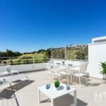 A balcony with white furniture and a view of the mountains, overlooking the Estepona Golf Course.