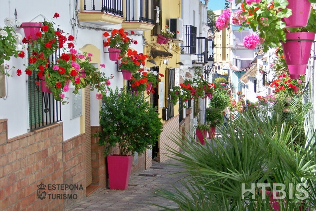A narrow street lined with pink flower pots in Estepona.