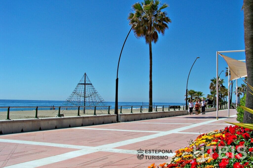 A sidewalk with palm trees and flowers by a townhouse in Estepona.